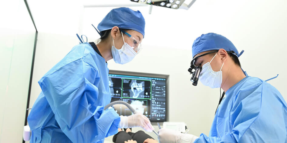 患者の歯の手術を行う2人の歯科医師